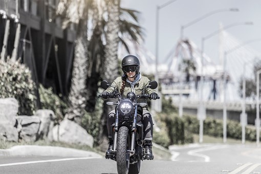 Front angle of a person riding a motorcycle on a city street. opens in a new window
