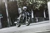  Three-quarter front angle of a person riding a motorcycle on a city street.