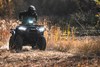 Front view of a person riding an ATV off-road with the headlights on.