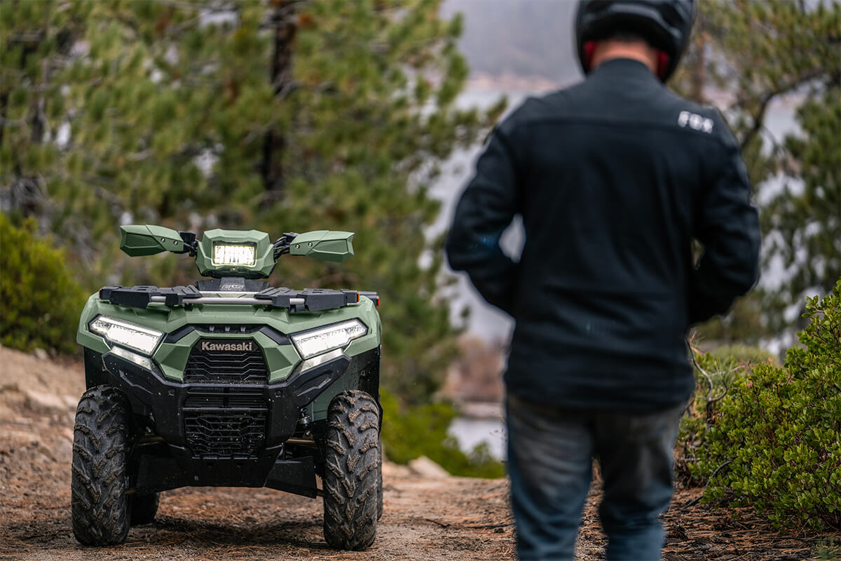Front view of an ATV parked off-road with a person in the foreground.