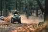 Front view of a person riding an ATV through the woods.