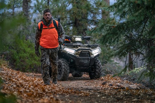 Front view of an ATV parked off-road with a person in the foreground. opens in a new window