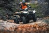 Front three-quarter view of a person riding an ATV off-road. 