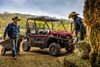 Three-quarter front angle of a parked side x side and people working the farm.