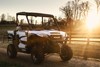 Front three-quarter view of a side x side by a fence at sunset.