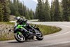 Three-quarter front angle of a person riding a motorcycle on a highway.