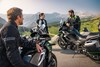 Two motorcycles parked at a scenic overlook with people standing nearby.