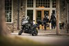 Side angle of a parked motorcycle with people in the background entering a building.