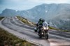 Three-quarter front angle of a person riding a motorcycle on a highway with cracked pavement.