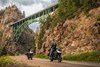  Three-quarter front angle of a people riding motorcycles under a bridge.