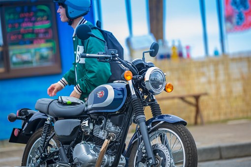 Three-quarter front angle of a person standing near a parked motorcycle. opens in a new window