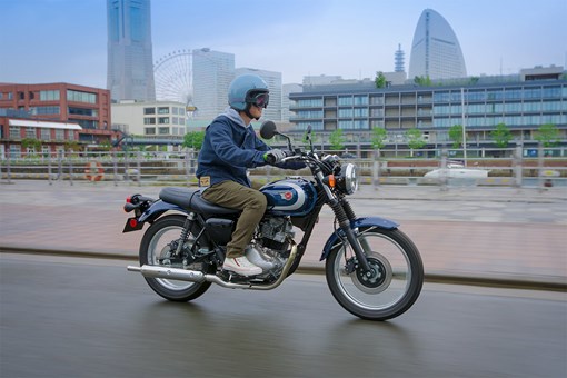 Side angle of a person riding a motorcycle on a street. opens in a new window