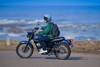 Side angle of a person seated on a motorcycle on a roadway.