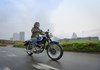 Three-quarter front angle of a person riding a motorcycle on a road.