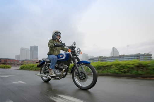 Three-quarter front angle of a person riding a motorcycle on a road. opens in a new window