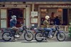 Side angle of two people seated on separate motorcycles.