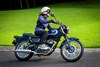 Side angle of a person riding a motorcycle on a road.