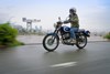 Profile angle of a person riding a motorcycle on a street.