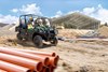 Three-quarter front angle of a person driving a side x side at a construction site.