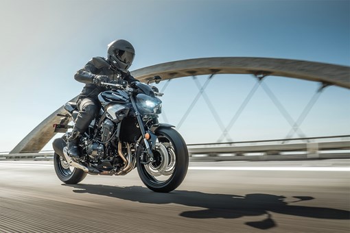 Side angle of a person riding a motorcycle on a bridge. opens in a new window