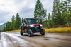 Front three-quarter angle of a ride side x side driving down a smooth dirt road.