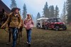 Three-quarter front angle of a side x side towing a horse trailer next to a mother and daughter.