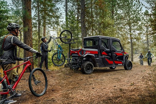 Rear three-quarter view of a side x side with a mountain bike mounted on the back. opens in a new window