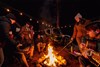 Campfire scene with people and a side x side in the background.