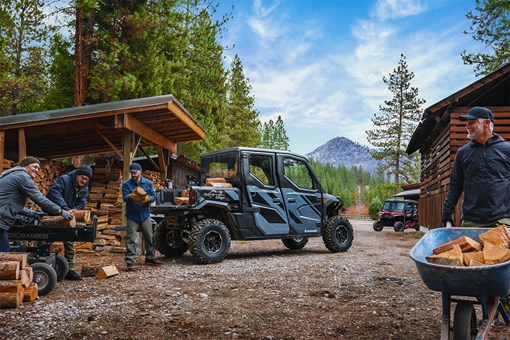 Rear three-quarter view of a side x side next to men splitting logs. opens in a new window