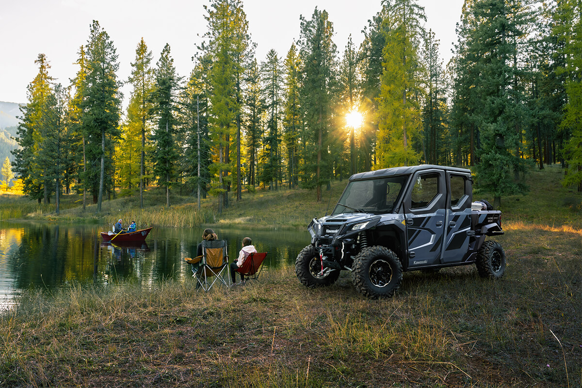 A side x side parked at a lake at dawn with people fishing.