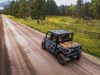 Side x side with four people and a cargo bed full of firewood on a dirt road.