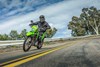 Front angle of a person riding a dual-sport motorcycle on a two-lane road.