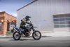 Side view of a person riding a motorcycle in front of a warehouse.