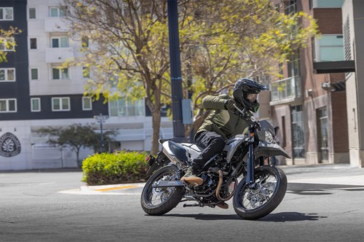 Front three-quarter view of a person riding a motorcycle around a city corner. opens in a new window