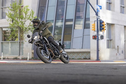 Front view of a person riding a motorcycle through an urban intersection.  opens in a new window