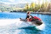 Front three-quarter angle of a woman riding a personal watercraft on the water.