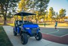 Three-quarter front angle of a Neighborhood Activity Vehicle parked near a basketball court.