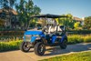 Three-quarter front angle of Neighborhood Activity Vehicle staged on a driveable sidewalk.