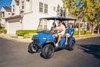 Three-quarter front angle of a family riding in a Neighborhood Activity Vehicle on a community roadway.