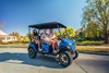 Side angle of a family riding in a Neighborhood Activity Vehicle on a community roadway.