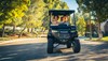 Front angle of a family riding in a Neighborhood Activity Vehicle on a community roadway.