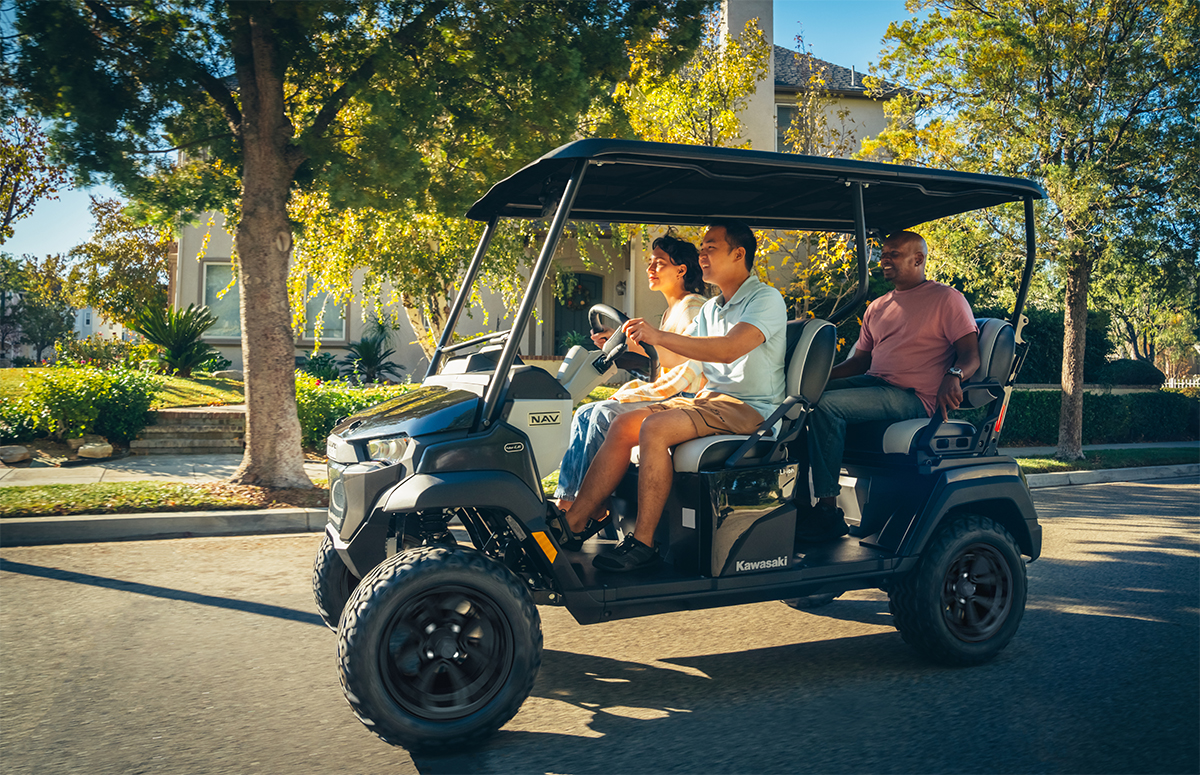 Side view of a family riding in a Neighborhood Activity Vehicle on a community roadway.