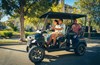 Side view of a family riding in a Neighborhood Activity Vehicle on a community roadway.