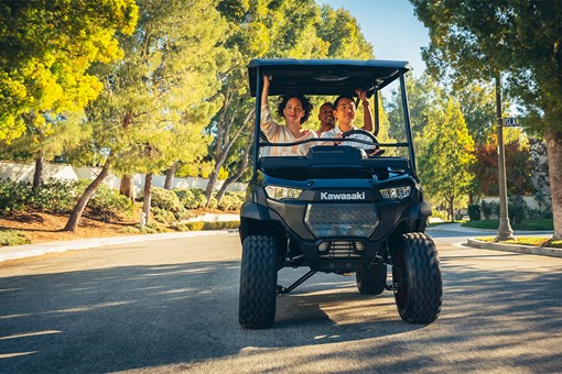 Front angle of a family riding in a Neighborhood Activity Vehicle on a community roadway. opens in a new window