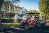 Three-quarter front angle of a family riding in a Neighborhood Activity Vehicle on a community roadway.