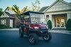 Three-quarter front angle of a Neighborhood Activity Vehicle staged near a community building.