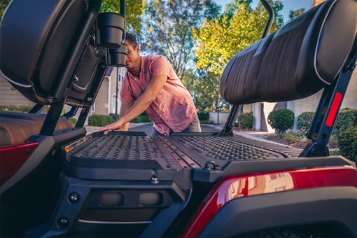 Close-up view of a person accessing the fold-flat seat system in a Neighborhood Activity Vehicle. opens in a new window