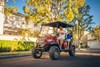 Three-quarter front angle of a family riding in a Neighborhood Activity Vehicle on a community street.