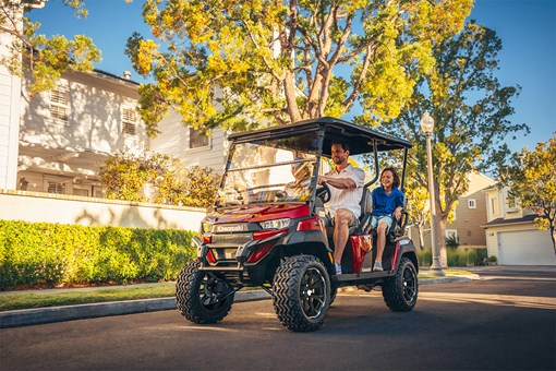 Three-quarter front angle of a family riding in a Neighborhood Activity Vehicle on a community street. opens in a new window