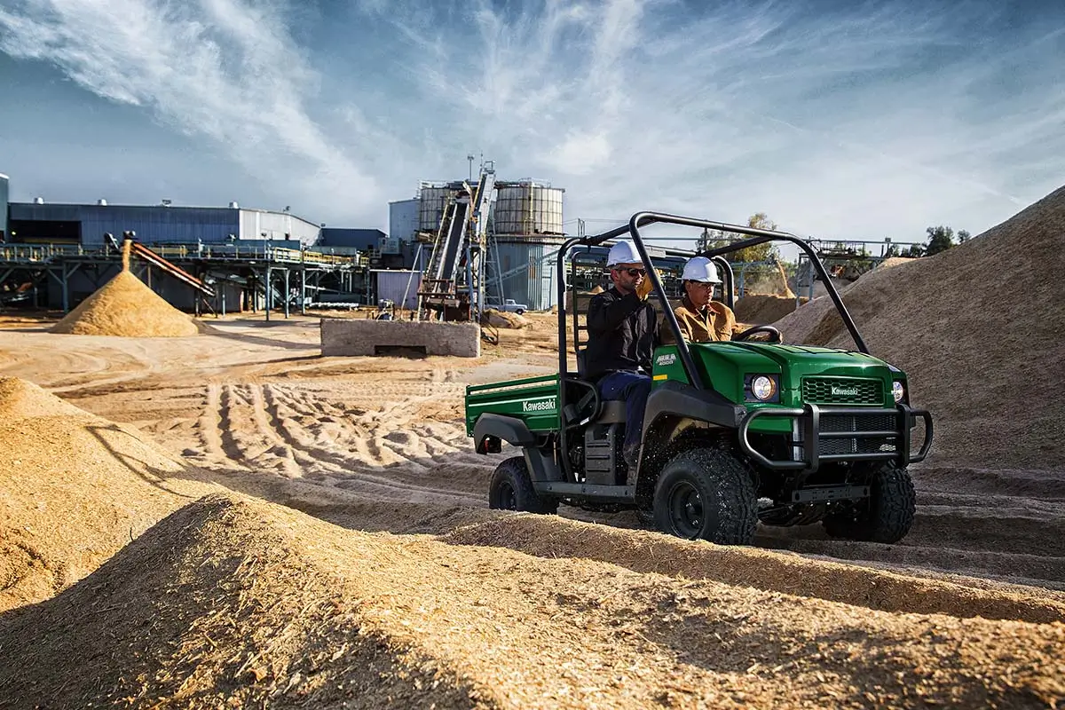 Three-quarter front angle of two people riding in a side x side on a jobsite.